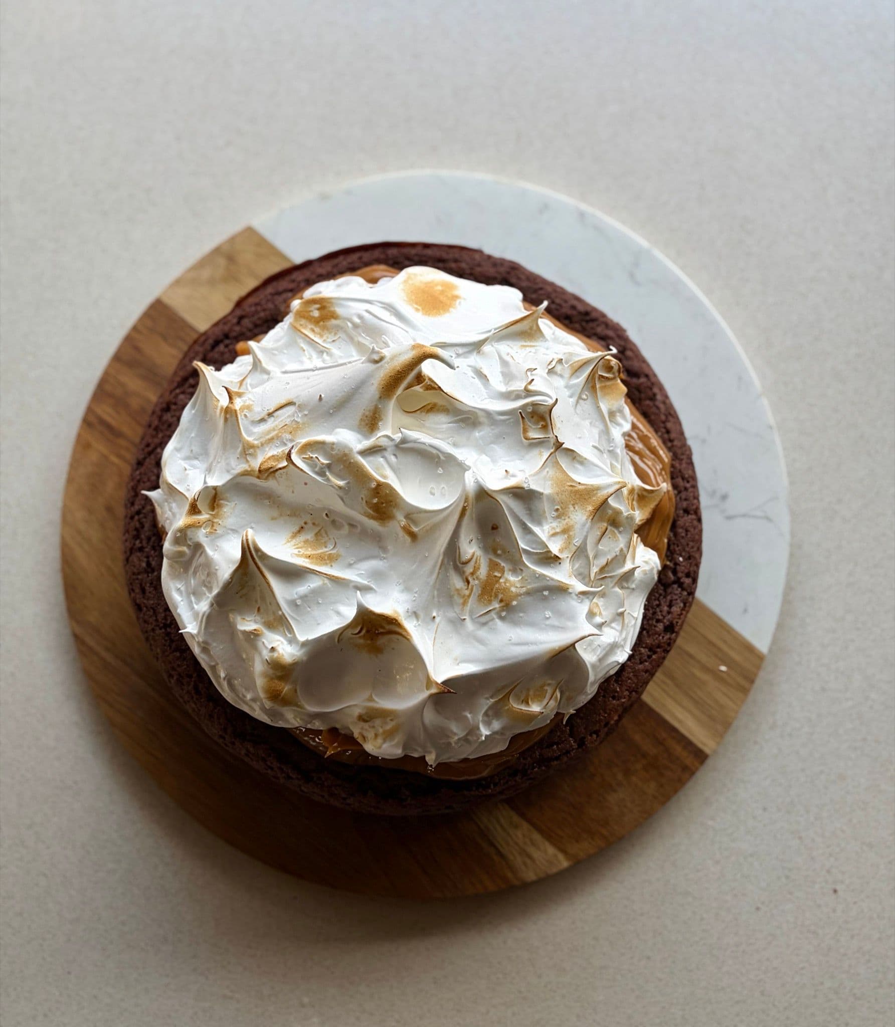 A whole marquise topped with torched Italian meringue on a wooden board