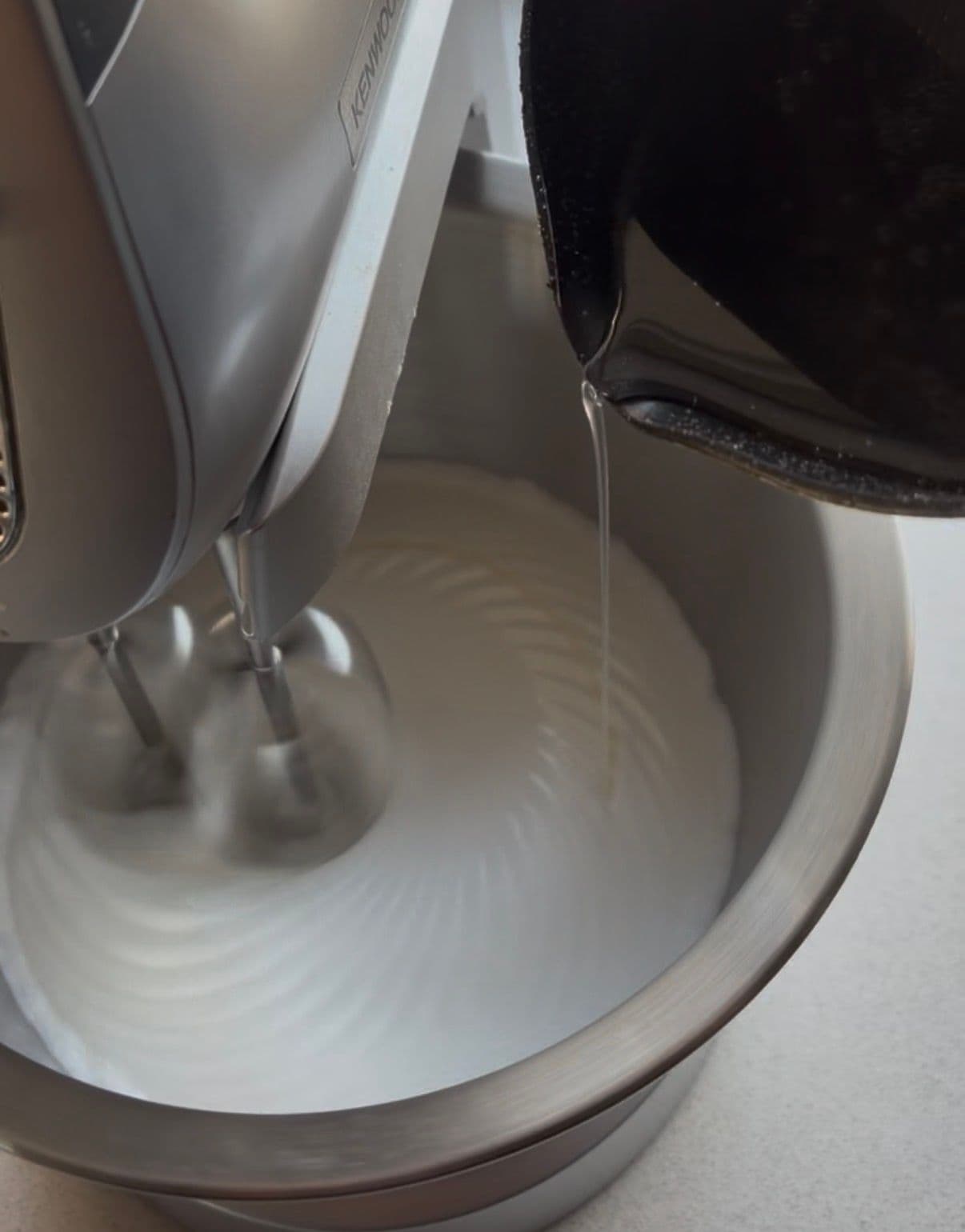 Pouring the hot syrup into the soft-peaked egg whites