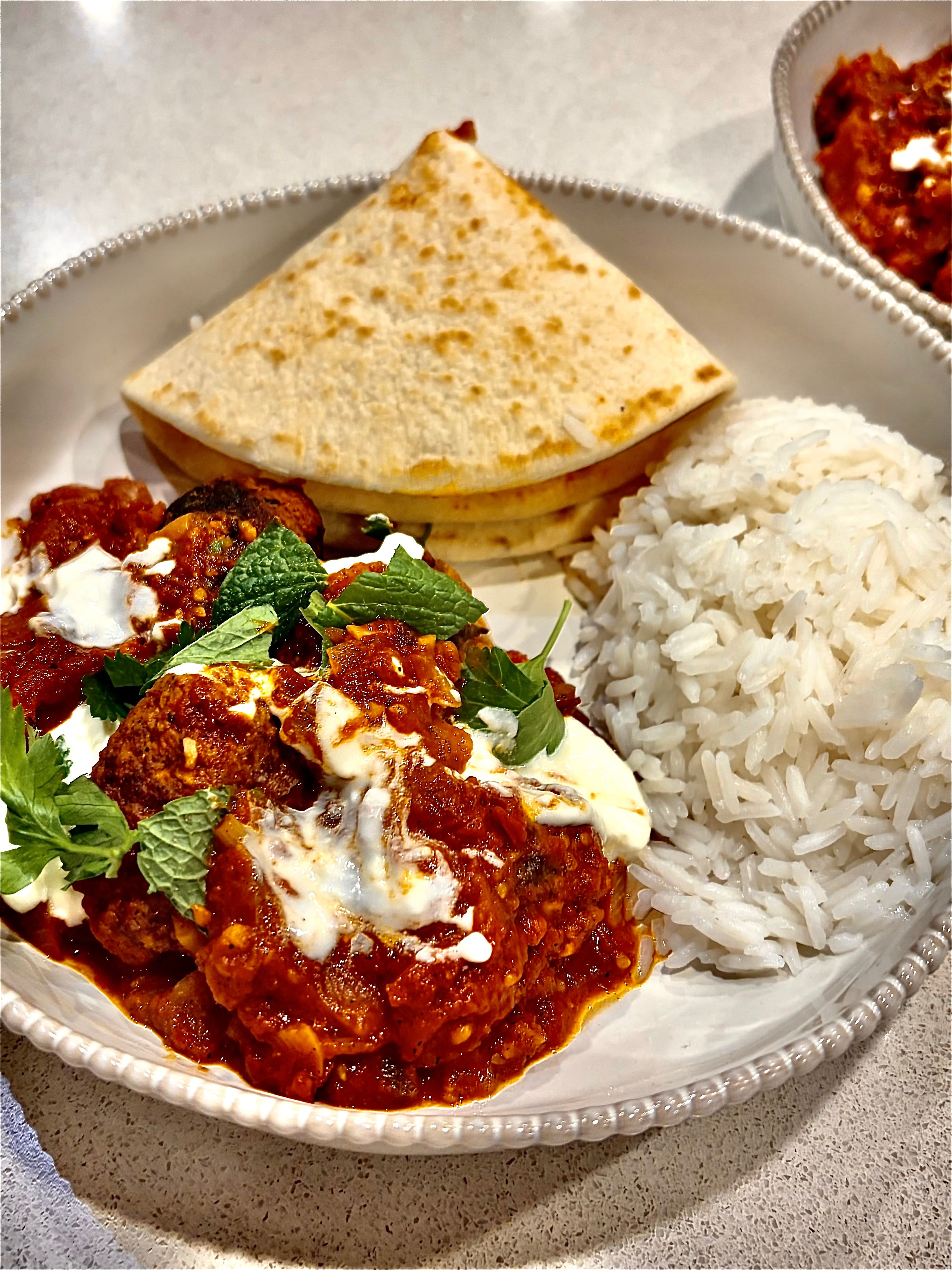 Lamb kofta in harissa tomato sauce served with rice and flatbread