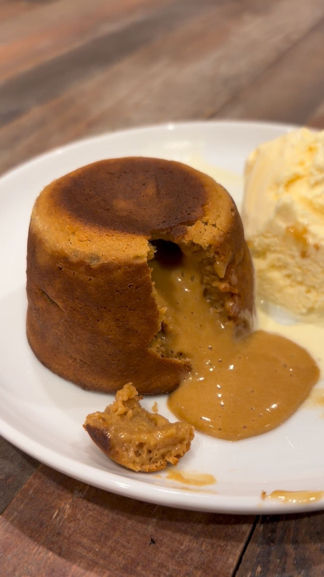 Volcán de dulce de leche with molten centre flowing onto a plate, served with vanilla ice cream