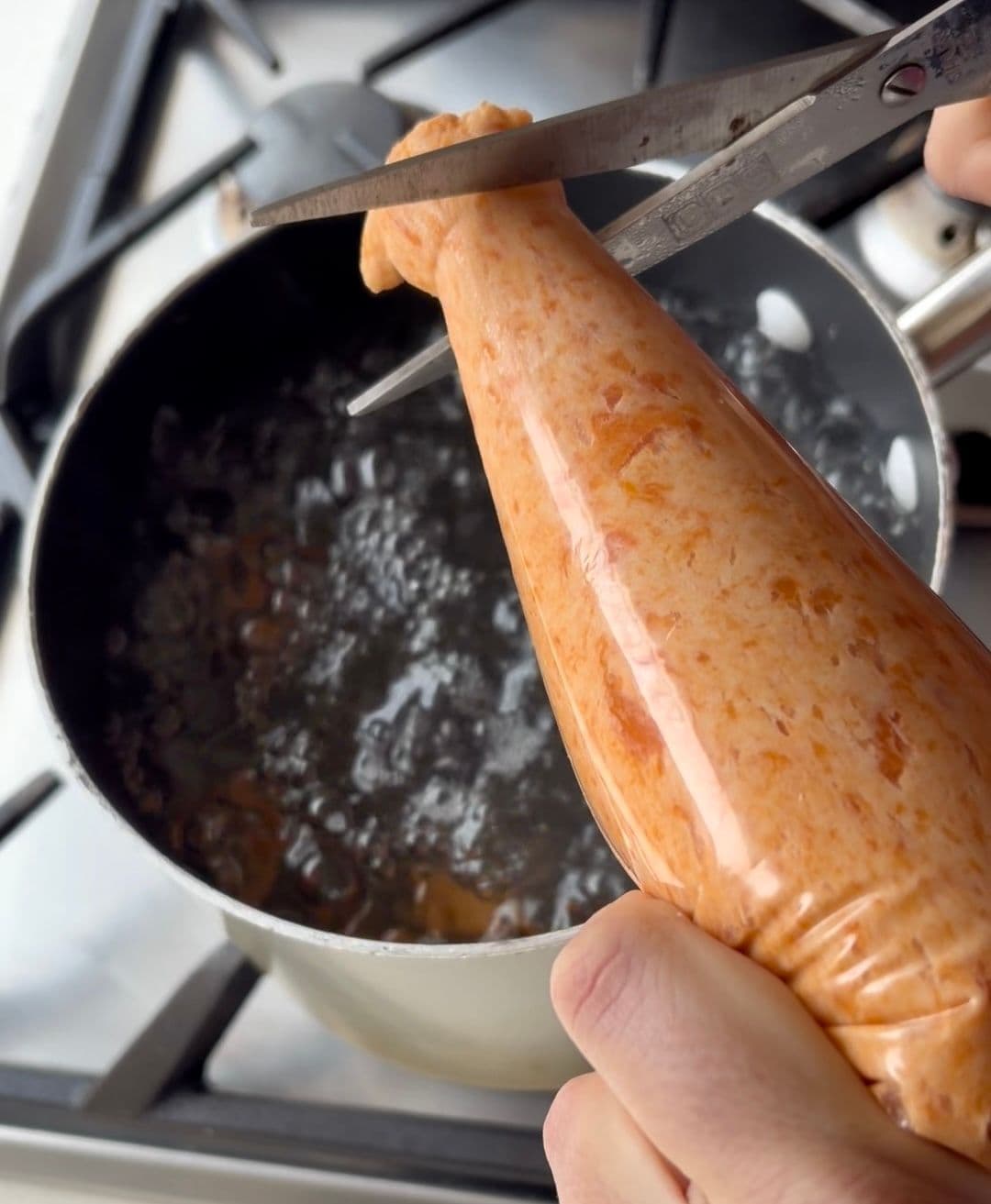 Piping gnocchi dough into boiling water, cutting with scissors