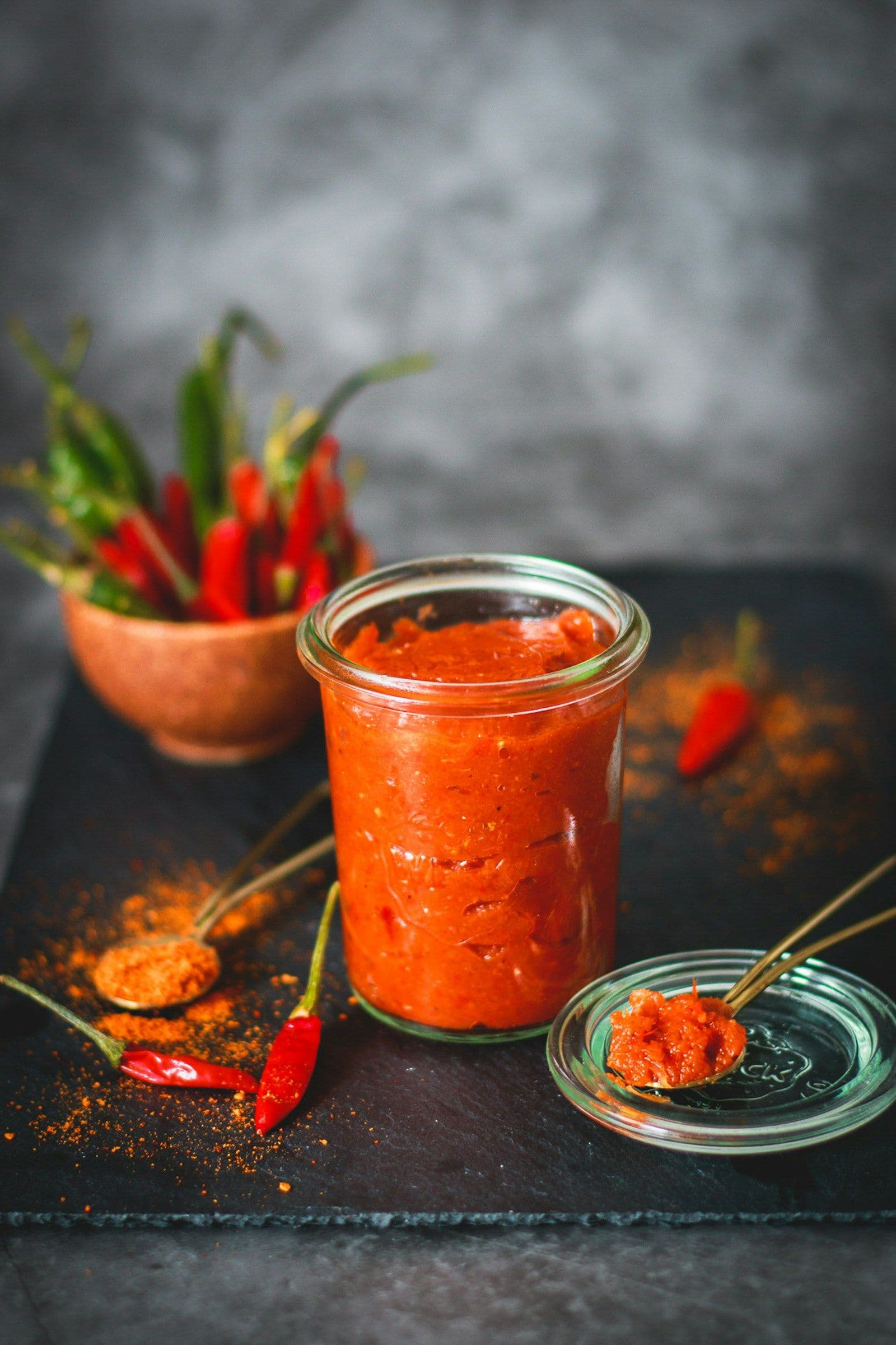 Homemade harissa paste in a jar with red chillies