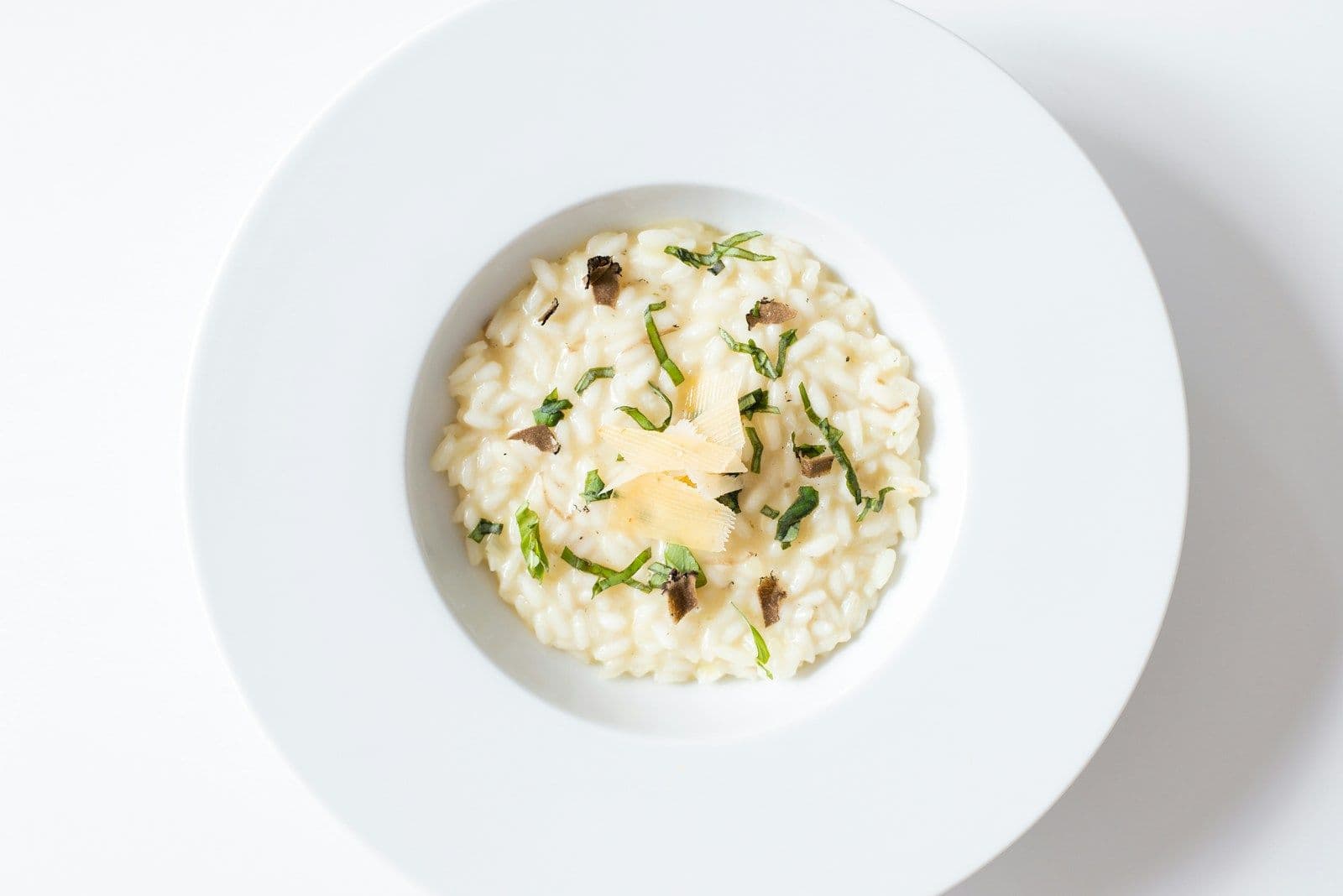 Wild mushroom risotto in a wide bowl topped with parmesan